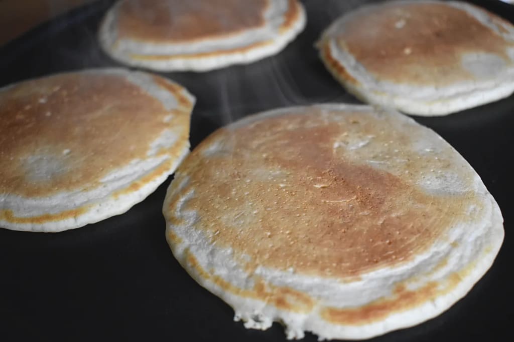 Four pikelets cooking on a griddle